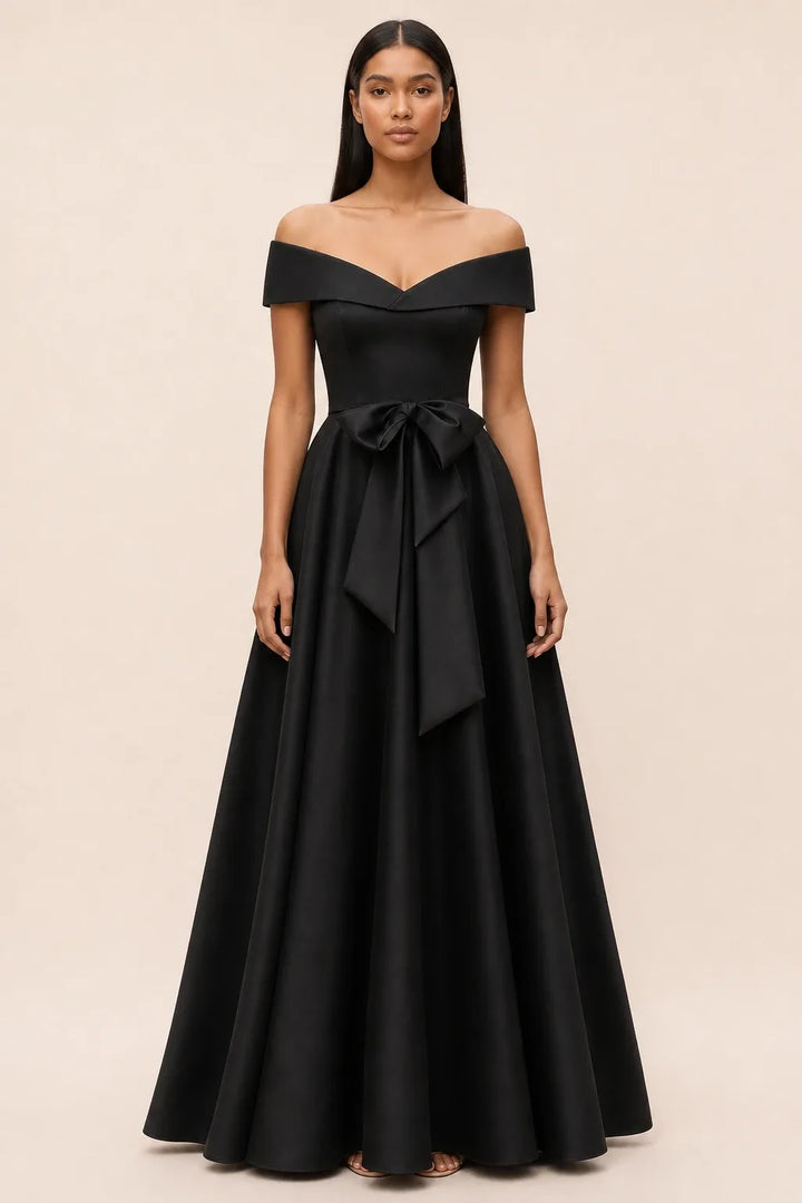 Black off-shoulder midi dress with bow detail, model in contrapposto stance
