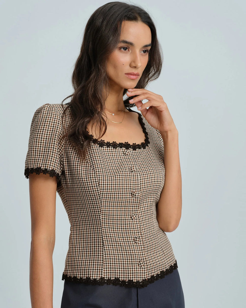 Close-up of lace trim detail on brown gingham fabric