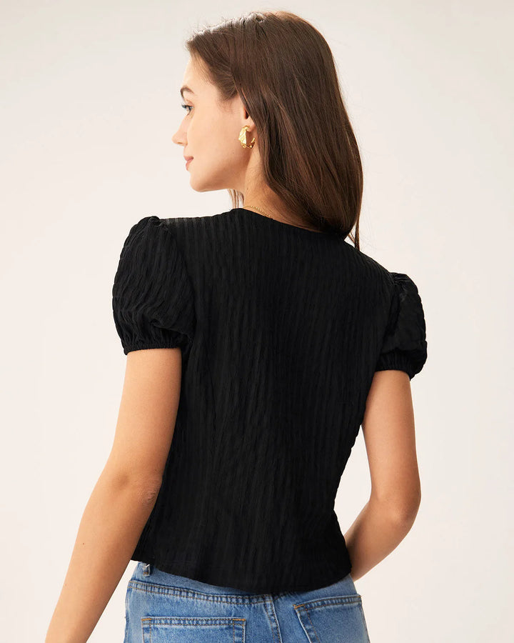 Black puff sleeve blouse with lace trim, model in side profile