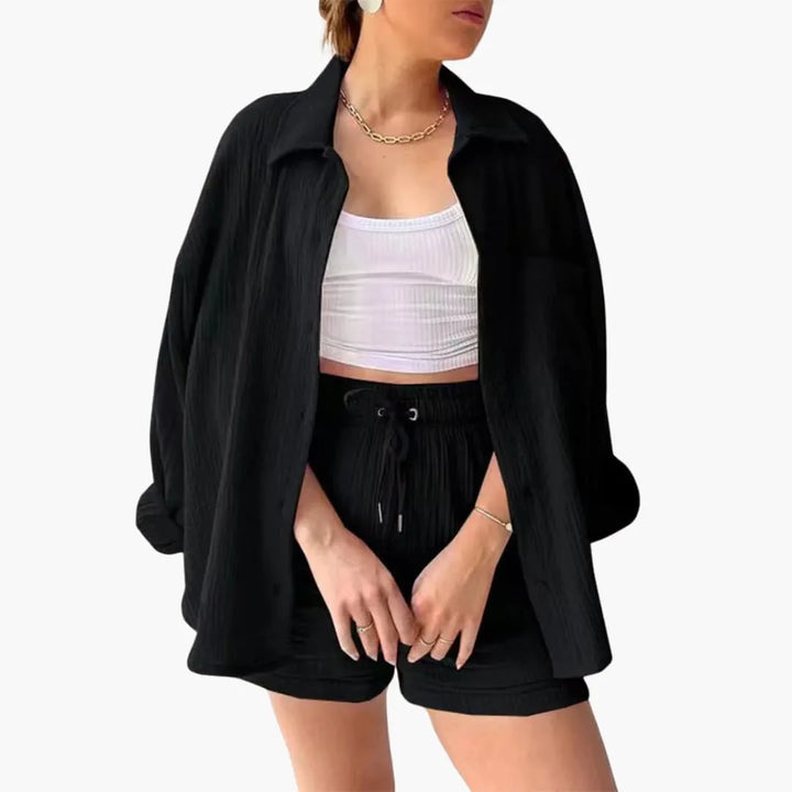 Model wearing a black crinkle button-up shirt and matching shorts set