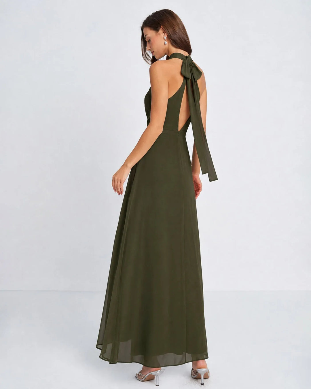 Woman in a floor-length green halter chiffon gown, side view