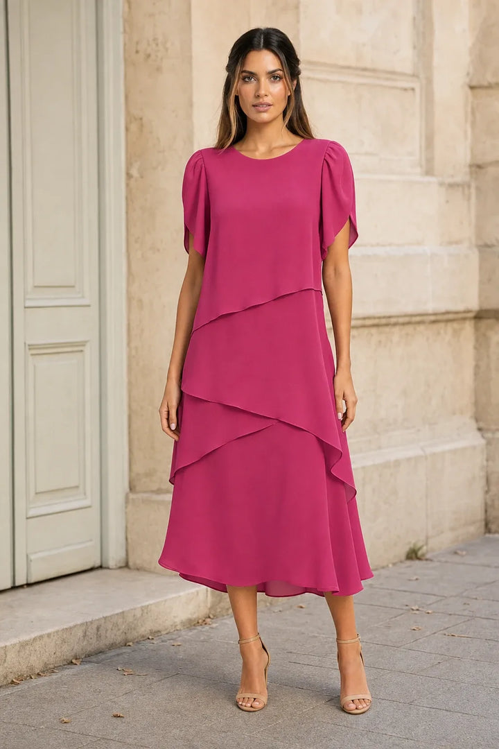 Pink tiered chiffon midi dress on a model in a contrapposto stance