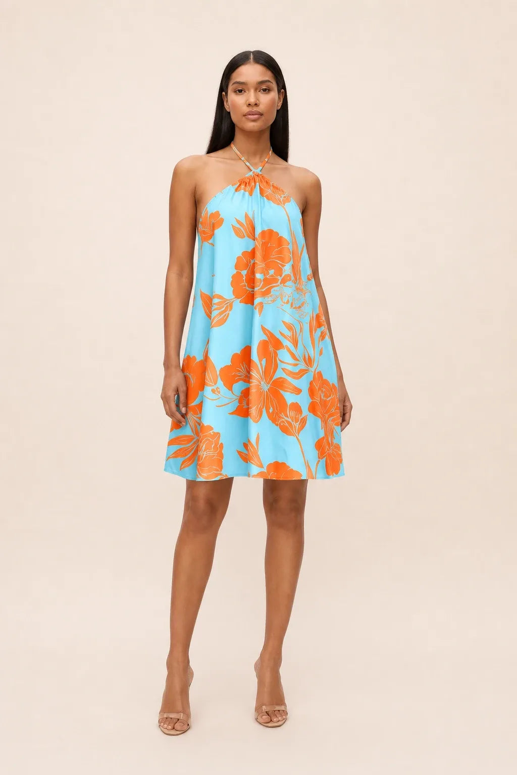 Model in sky blue floral halter mini dress, standing in contrapposto pose