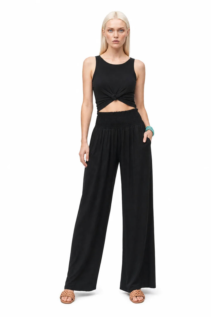 Black smocked wide-leg pants on a model in a contrapposto stance