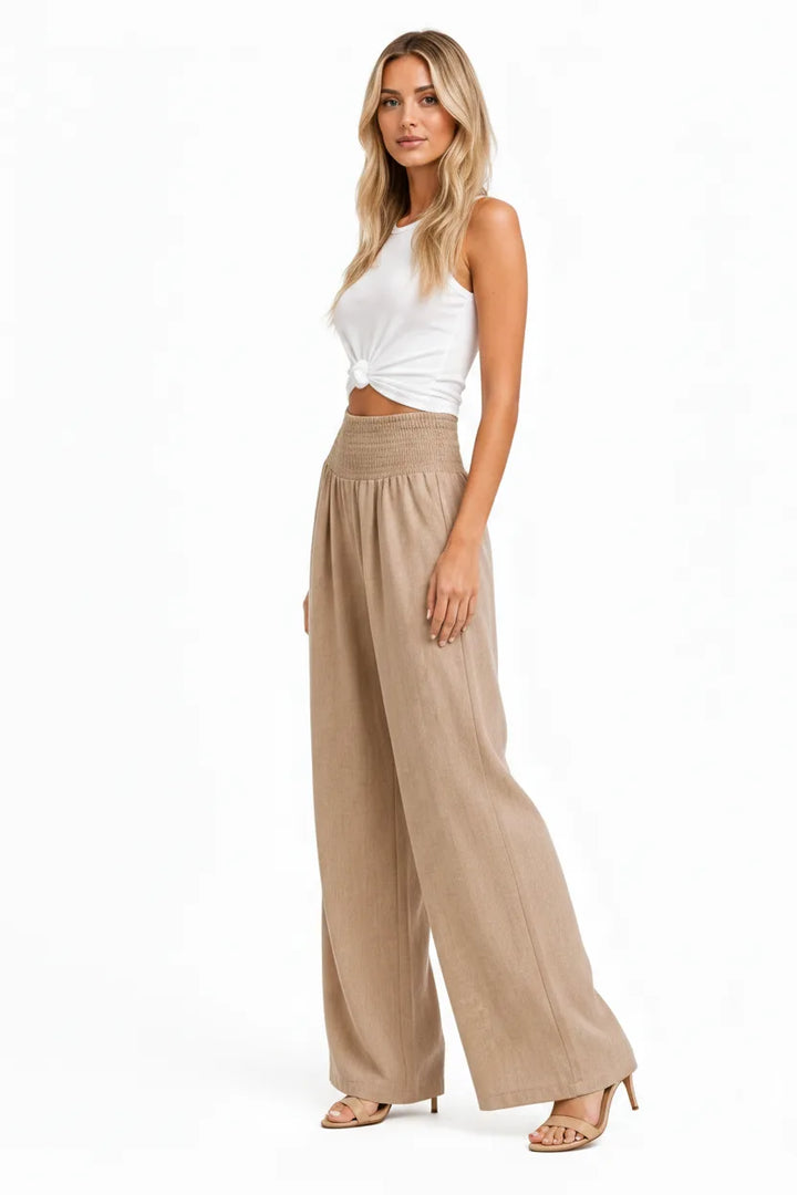 Khaki smocked wide-leg pants on a model at a three-quarter turn