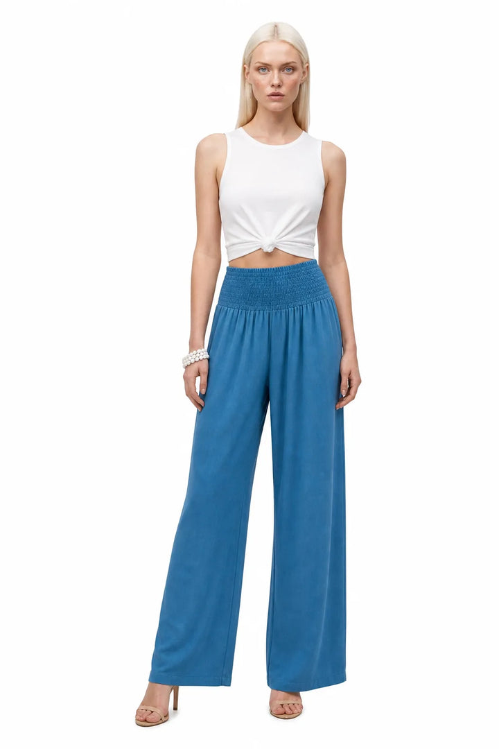 Peacock blue smocked wide-leg pants on a model in a contrapposto stance