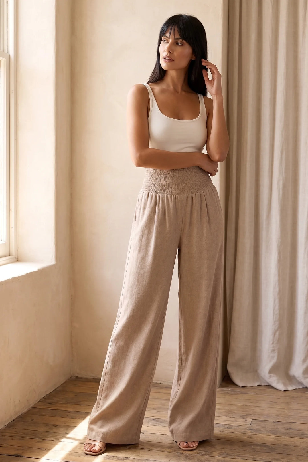 Model wearing khaki smocked wide leg pants in lifestyle setting