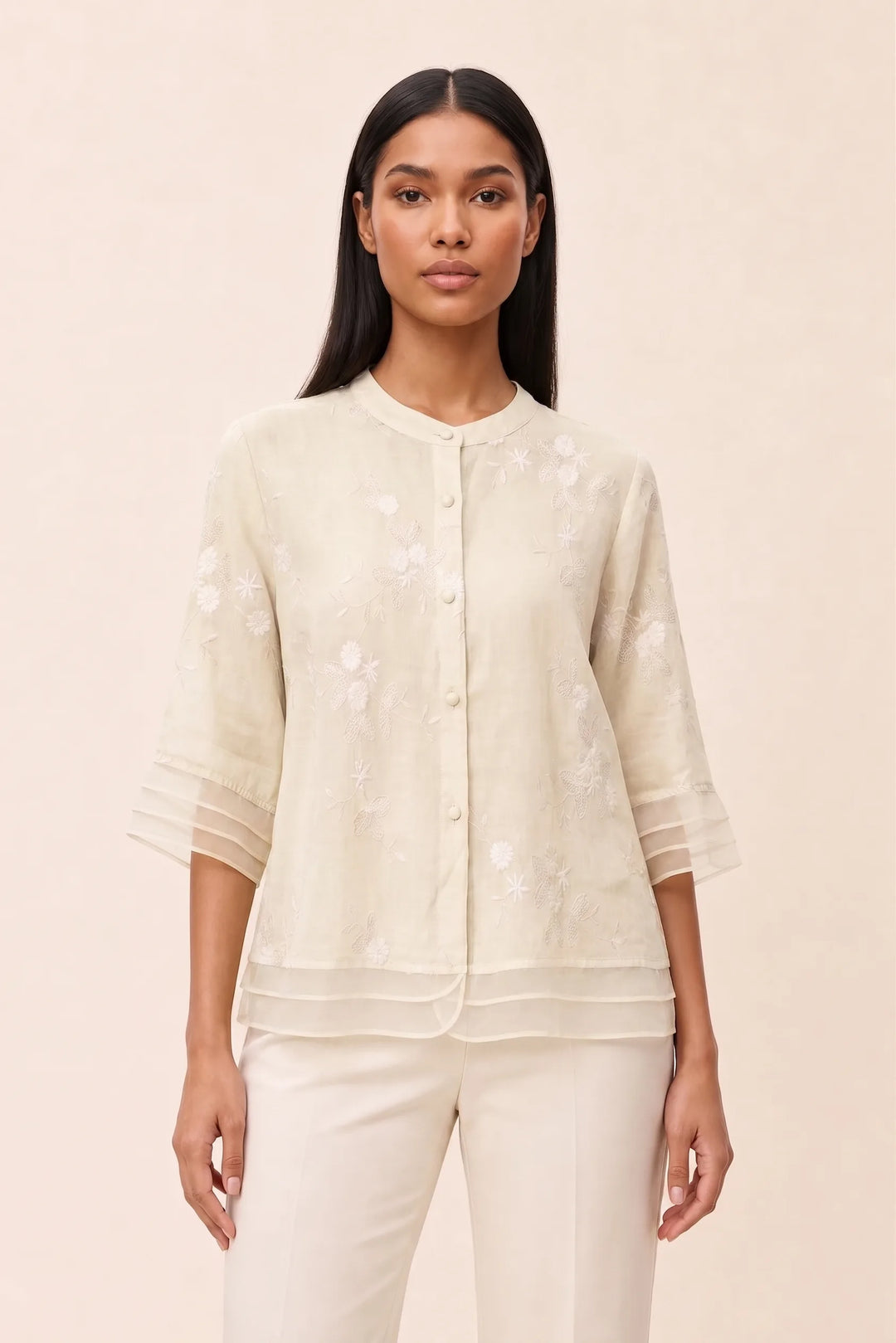 Ivory floral embroidered blouse on model in contrapposto stance