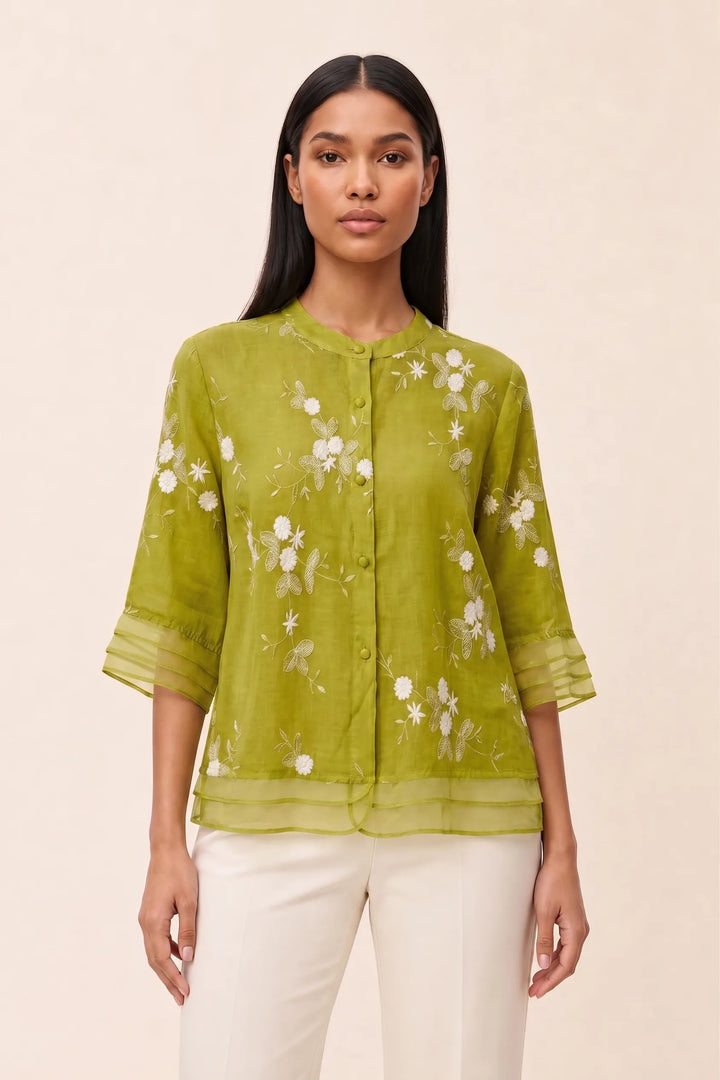 Lime green floral embroidered blouse on model in contrapposto stance