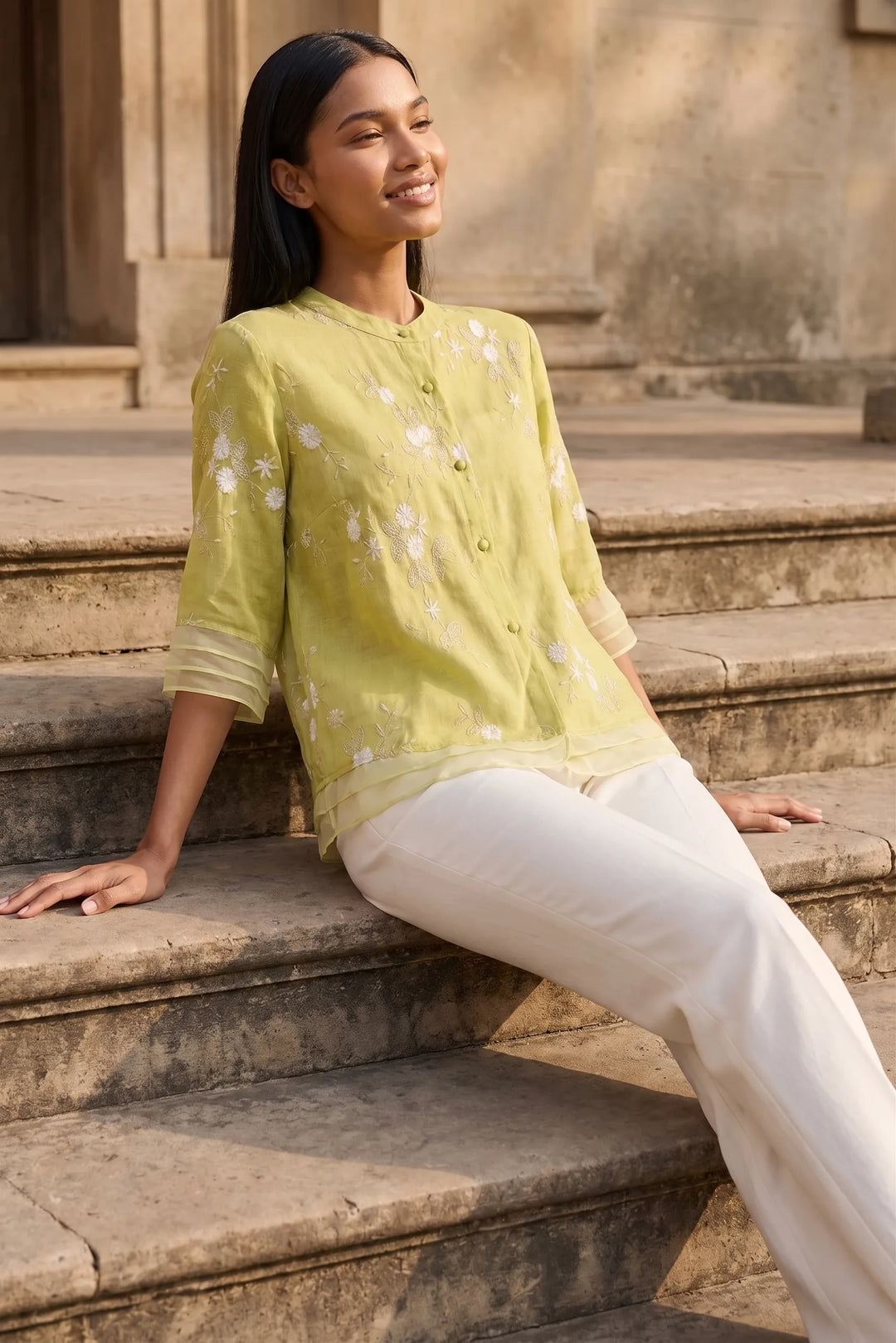 Model wearing yellow floral embroidered blouse in outdoor lifestyle setting
