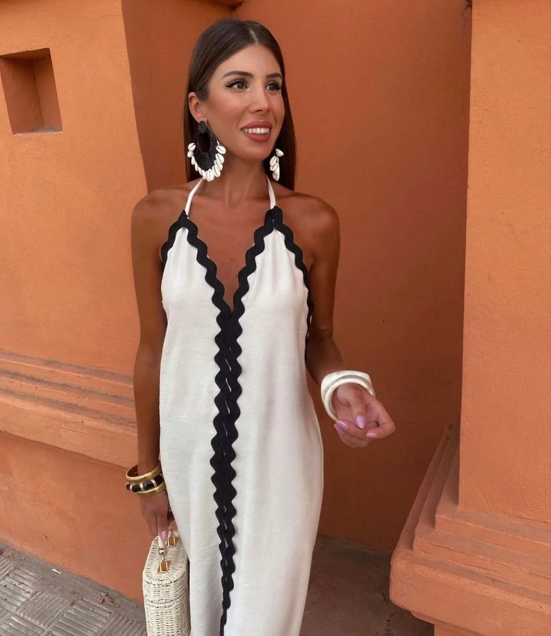Side view of a woman wearing a black maxi dress with ric rac trim