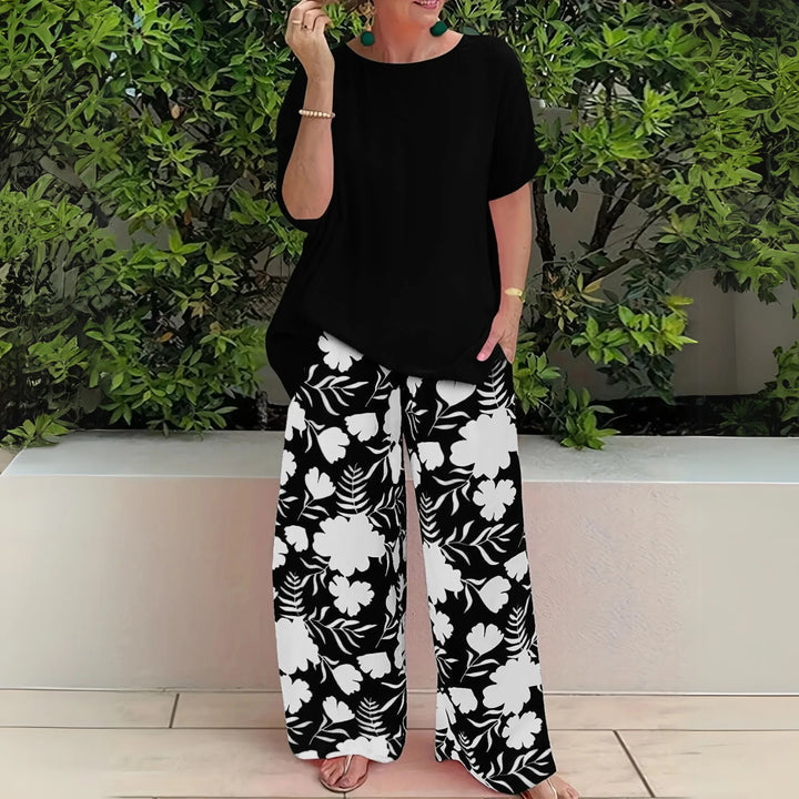 Woman in three-quarter turn wearing black floral wide-leg trousers and matching top