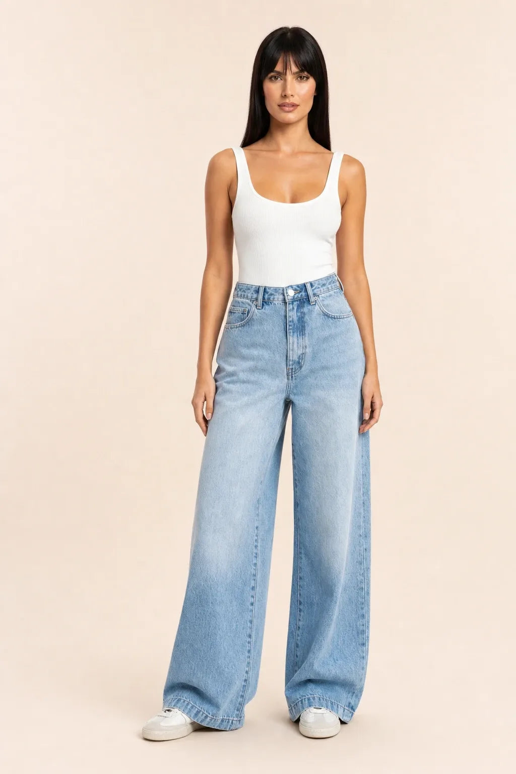 Woman in wide-leg blue jeans and white top, standing in contrapposto stance