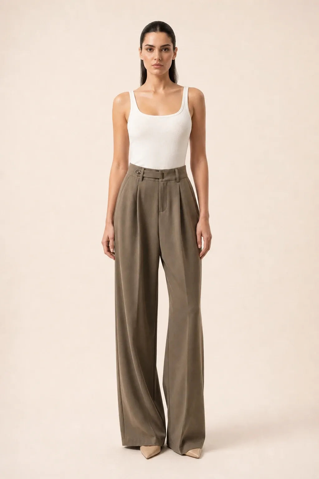 Woman in brown pleated wide-leg trousers standing in a contrapposto pose