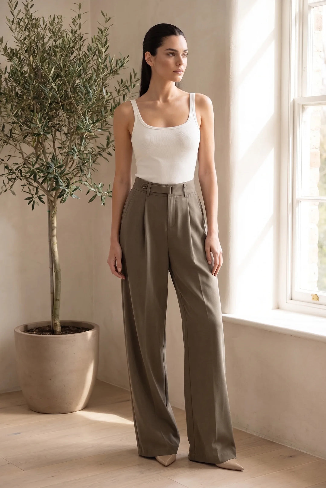 Woman wearing brown pleated wide-leg trousers in a relaxed lifestyle setting