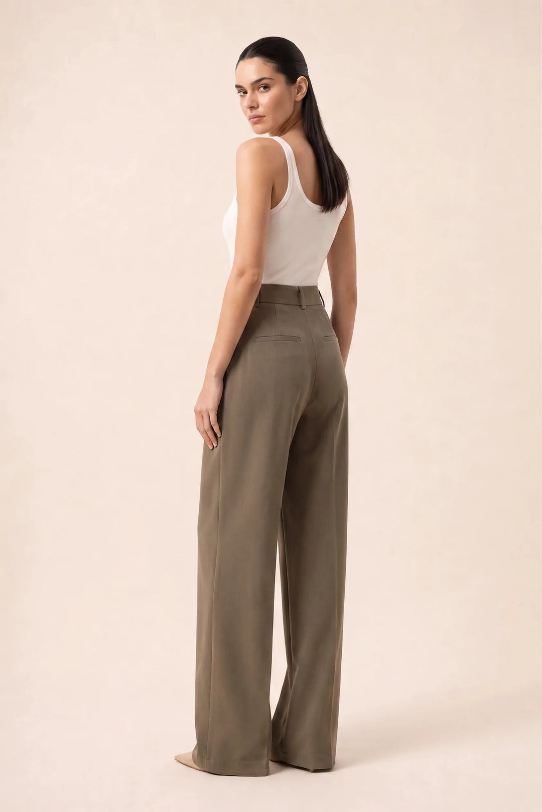 Woman in brown pleated wide-leg trousers shown from a three-quarter angle