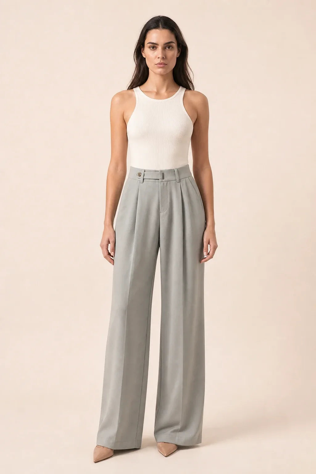 Woman in grey pleated wide-leg trousers standing in a contrapposto pose