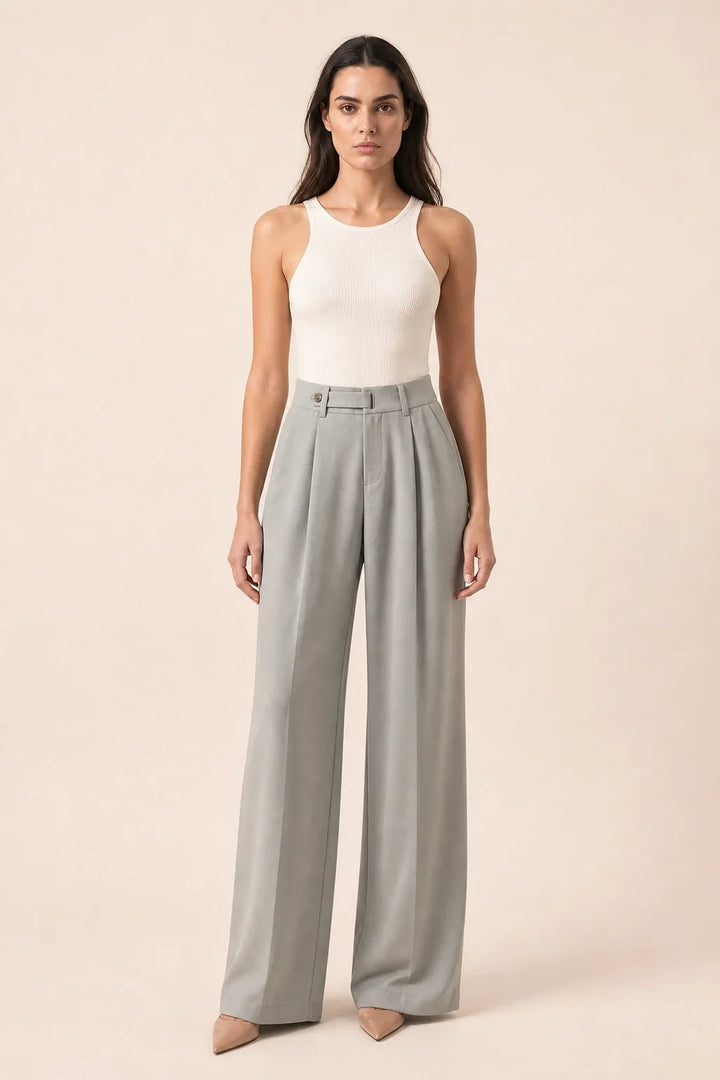 Woman in grey pleated wide-leg trousers standing in a contrapposto pose