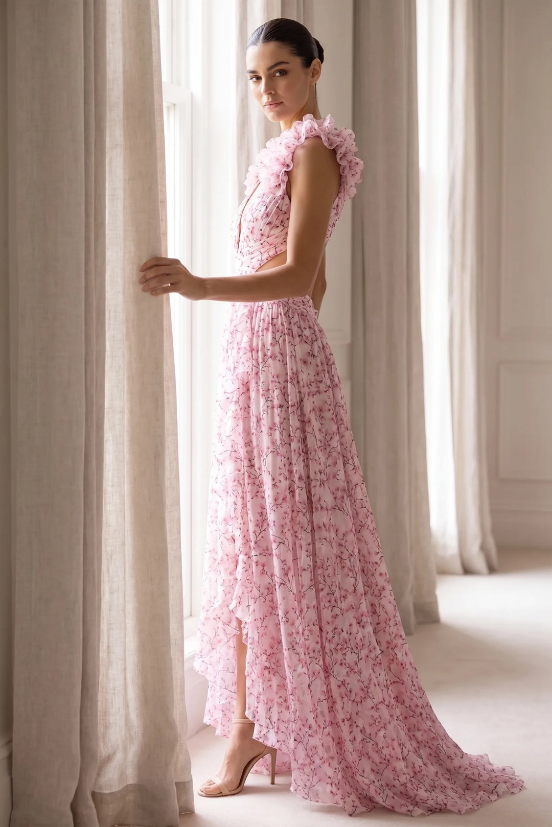 Model wearing pink ruffle-shoulder maxi dress in lifestyle setting