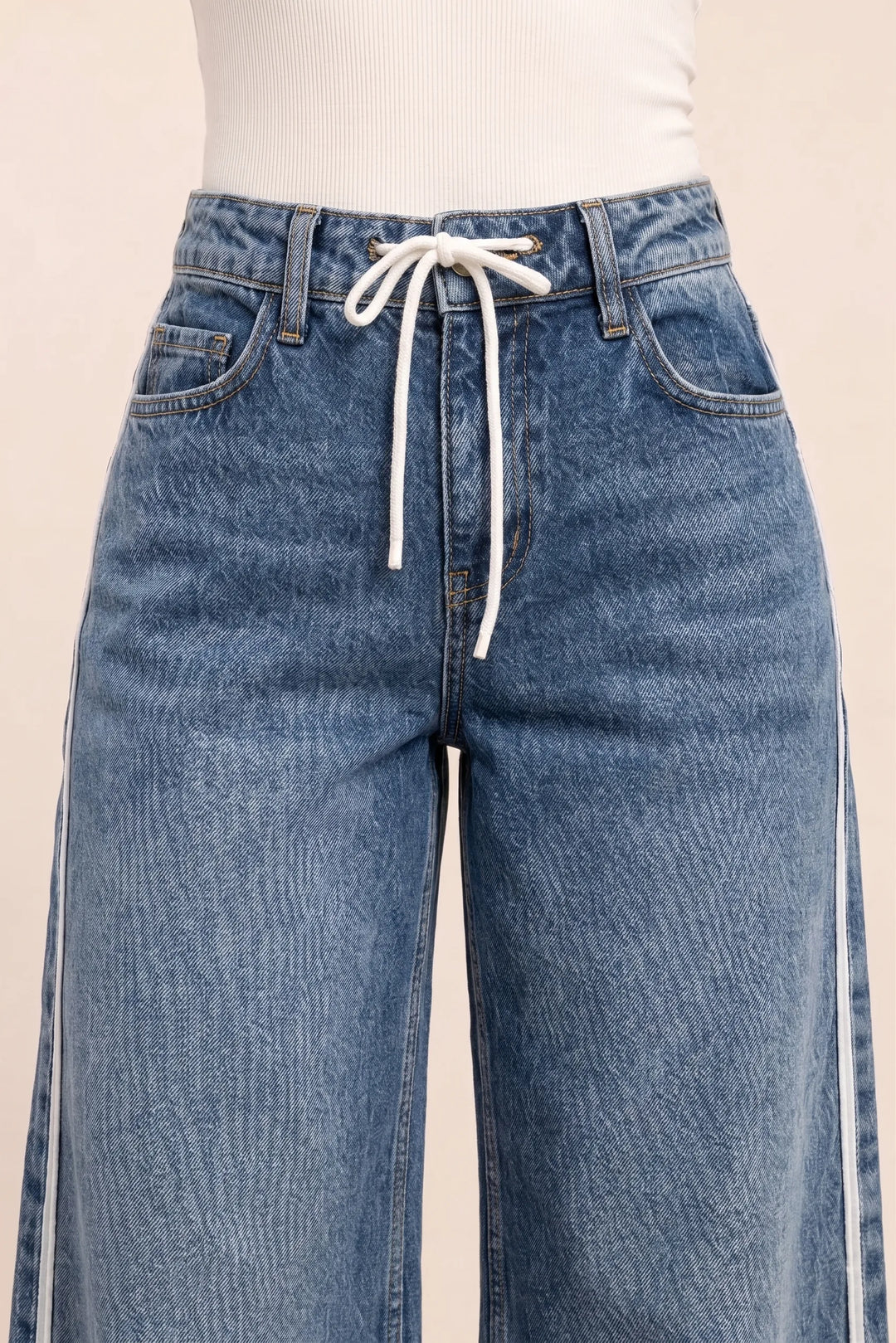 Close-up detail of white side stripe on medium blue wide-leg denim