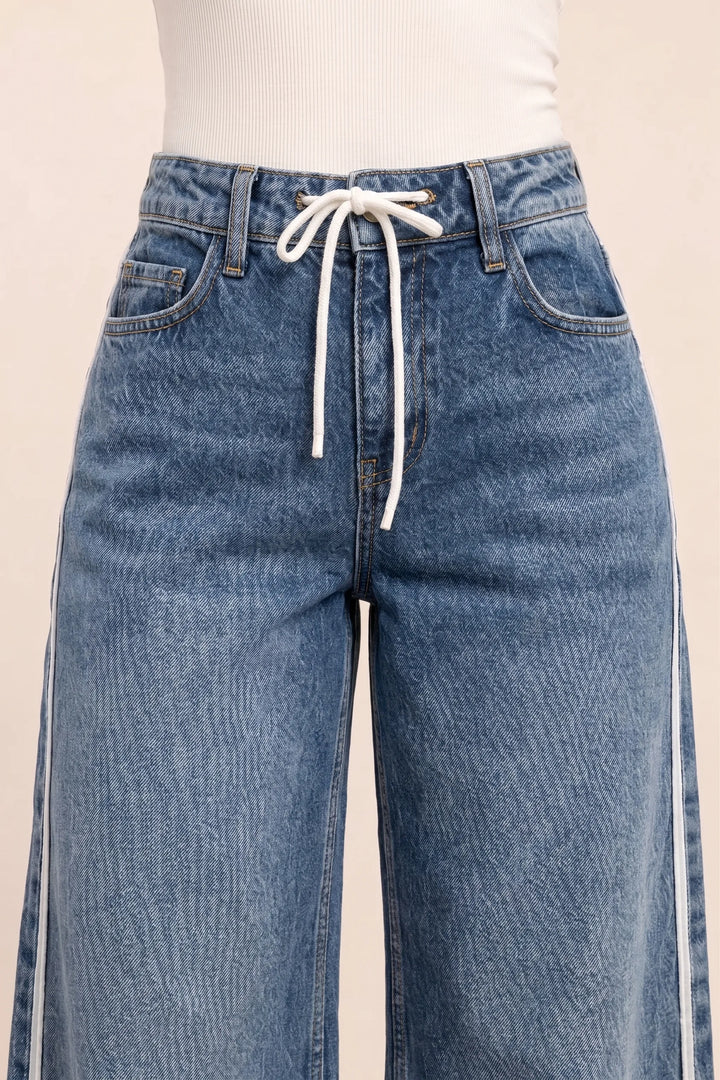 Close-up detail of white side stripe on medium blue wide-leg denim