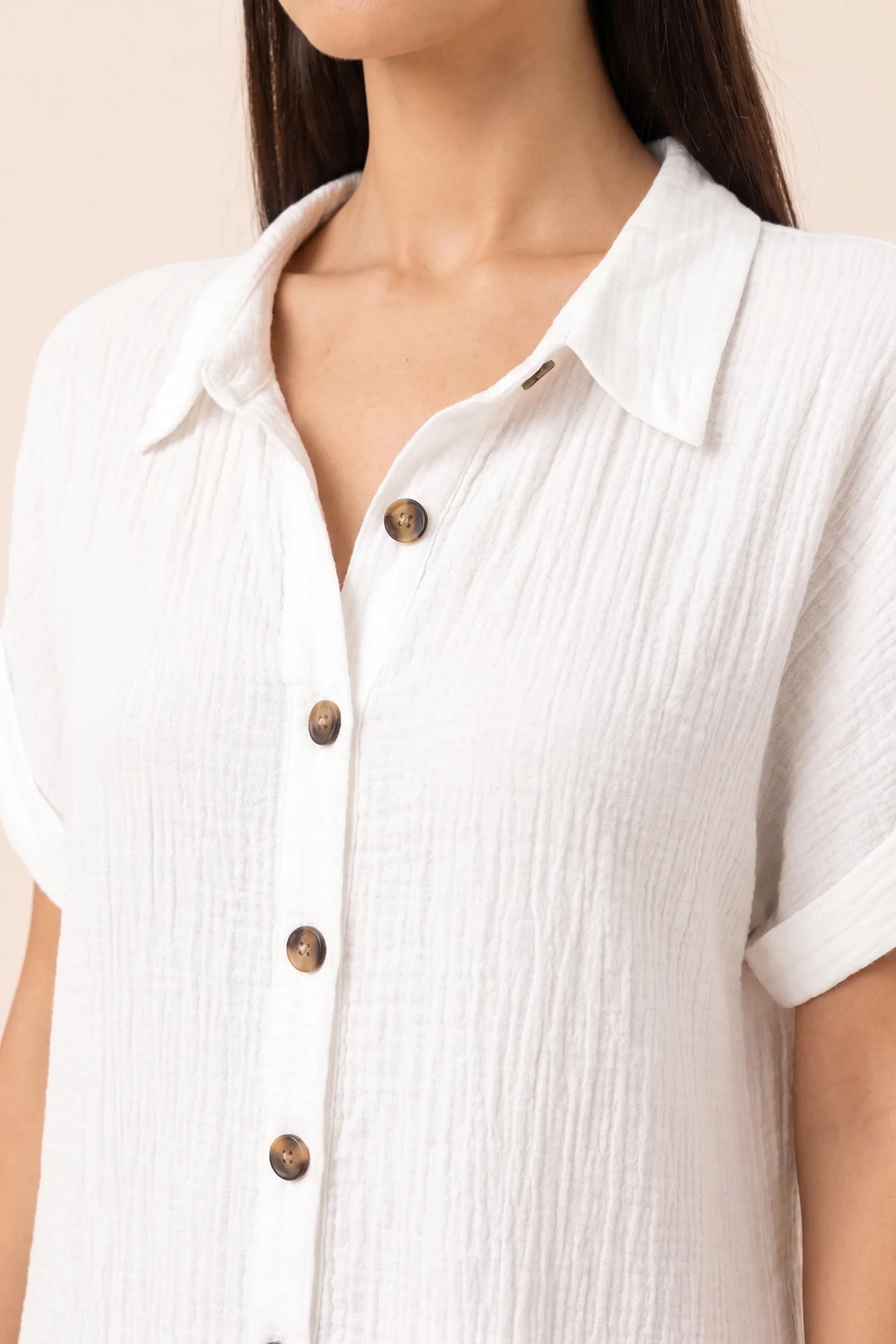 Close-up detail of white button-front shirt dress fabric and buttons