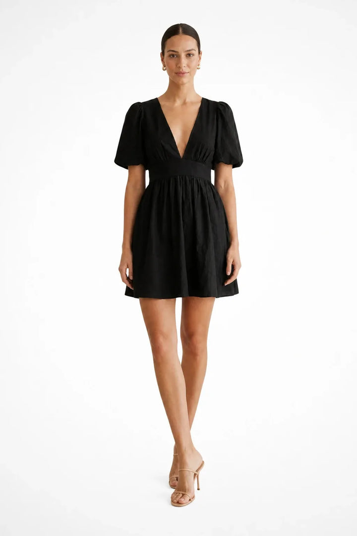 Black puff sleeve mini dress on model standing in contrapposto pose