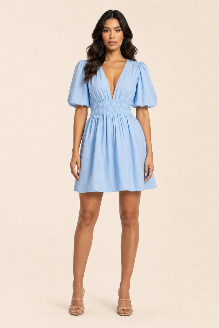 Blue puff sleeve mini dress on model standing in contrapposto pose