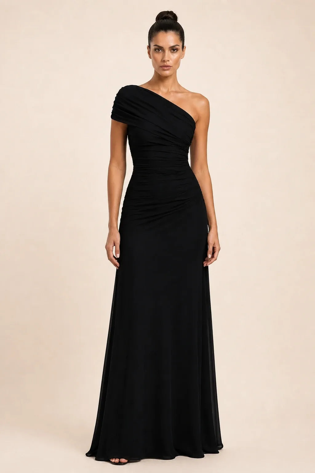 Woman in a black ruched-shoulder maxi gown standing in a contrapposto pose