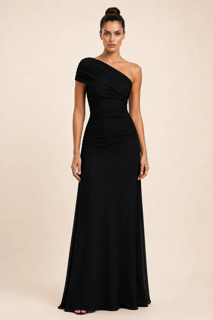 Woman in a black ruched-shoulder maxi gown standing in a contrapposto pose