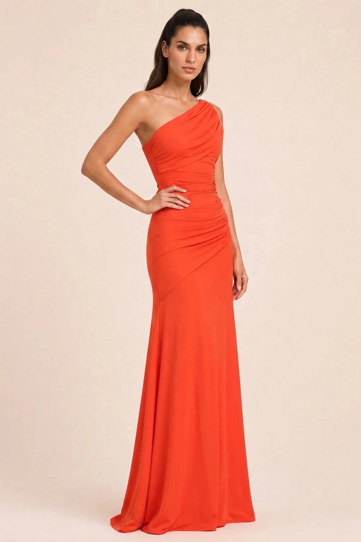 Woman in an orange ruched-shoulder maxi gown in a three-quarter turn