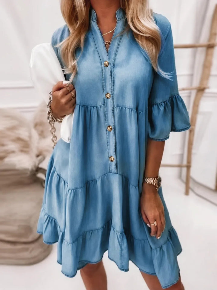 Woman in an ash blue tiered ruffle mini dress, side profile view