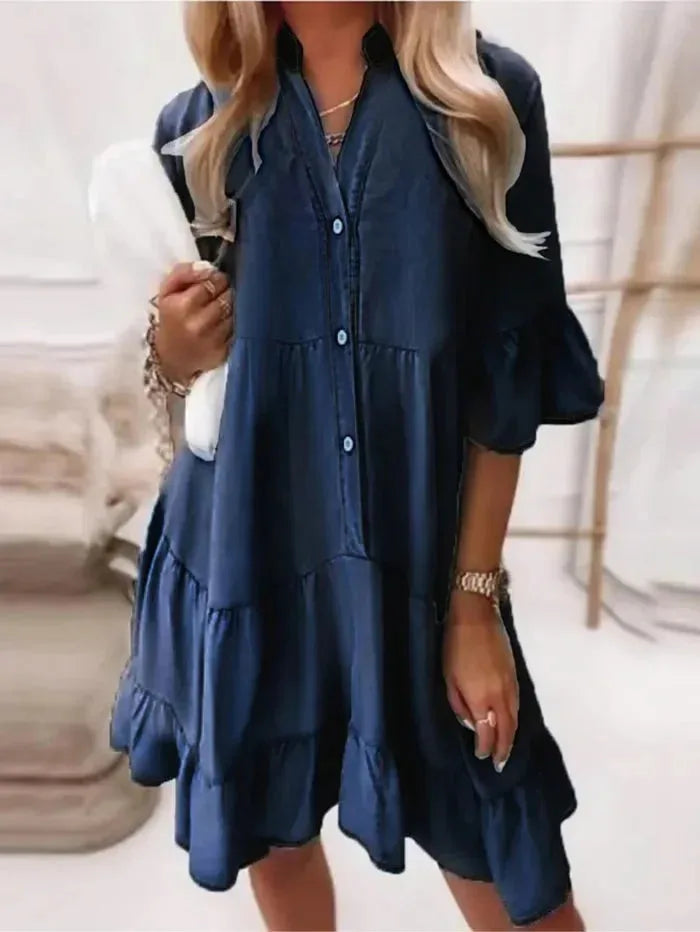 Woman in a dark blue tiered ruffle mini dress, shown at a three-quarter angle