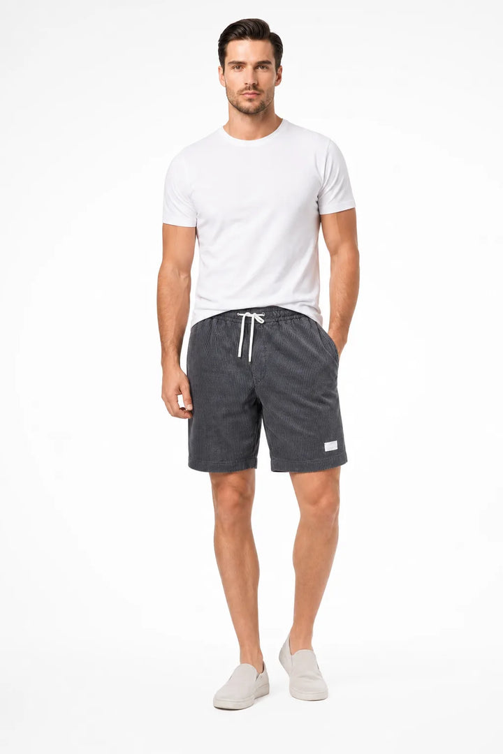 Grey corduroy drawstring shorts on a model in a contrapposto stance