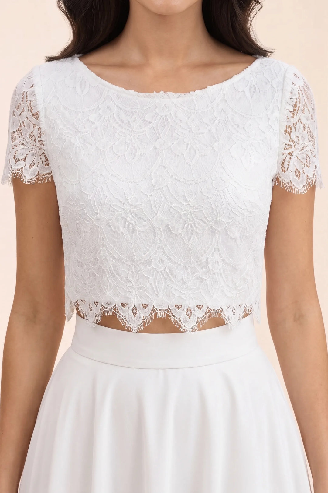 Close-up detail of white lace fabric texture on a crop top and midi skirt set