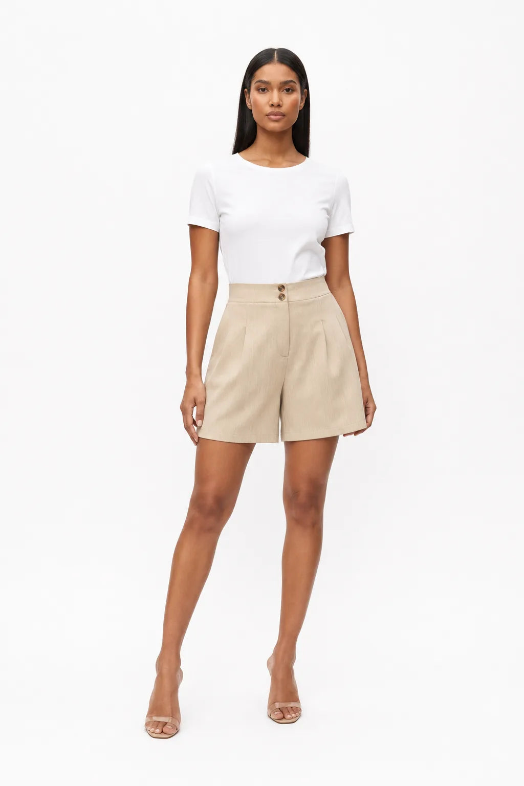 Apricot pleated Bermuda shorts on a model in a contrapposto stance