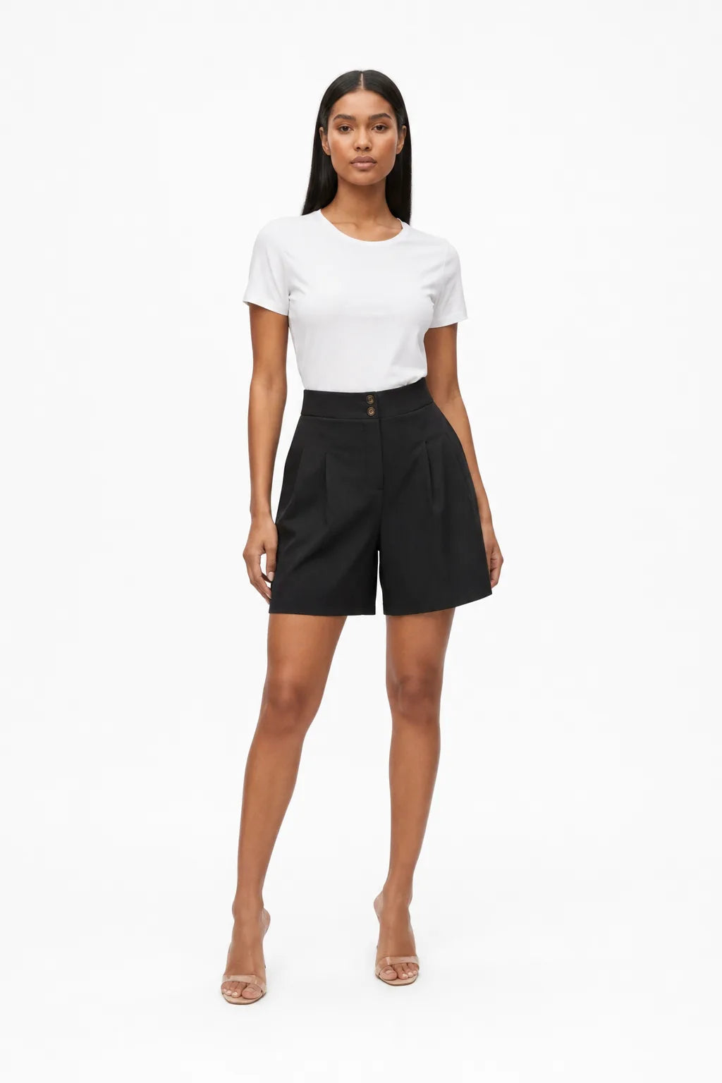 Black pleated Bermuda shorts on a model in a contrapposto stance