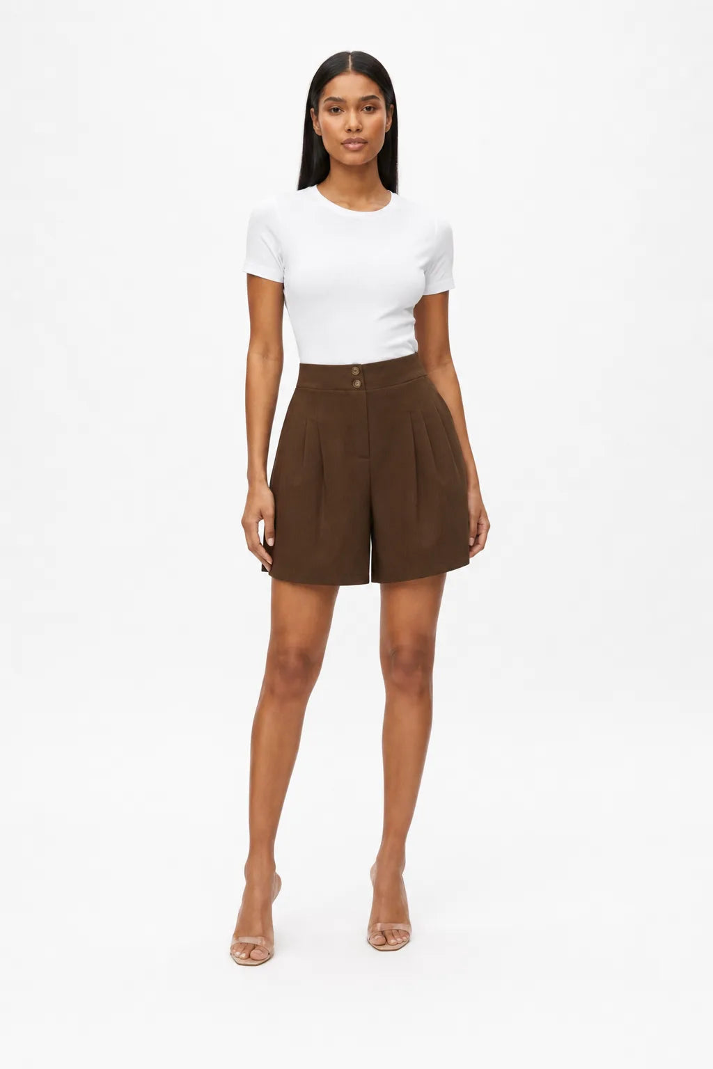 Brown pleated Bermuda shorts on a model in a contrapposto stance