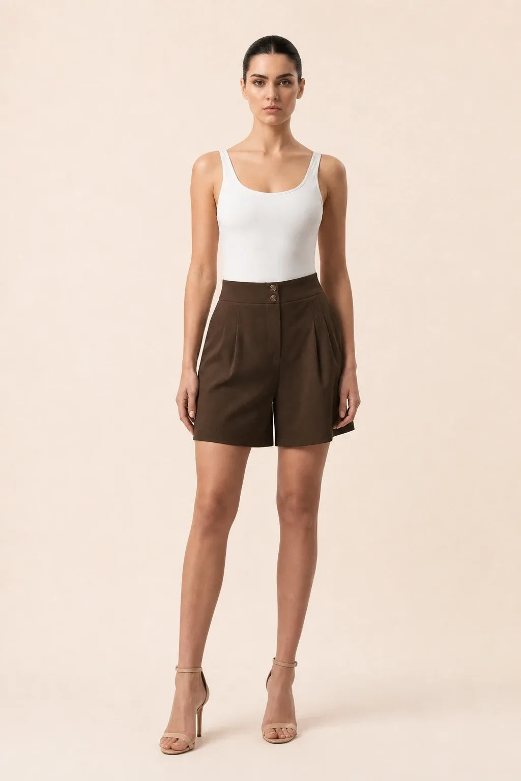 Brown pleated Bermuda shorts on a model in a contrapposto stance