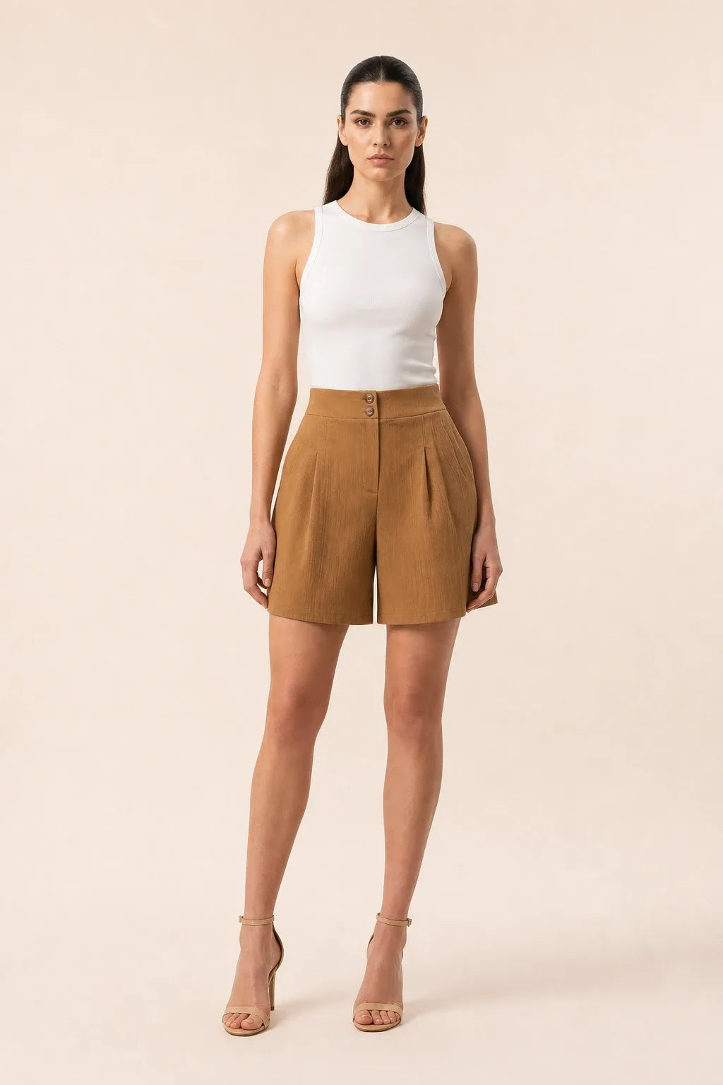 Khaki pleated Bermuda shorts on a model in a contrapposto stance