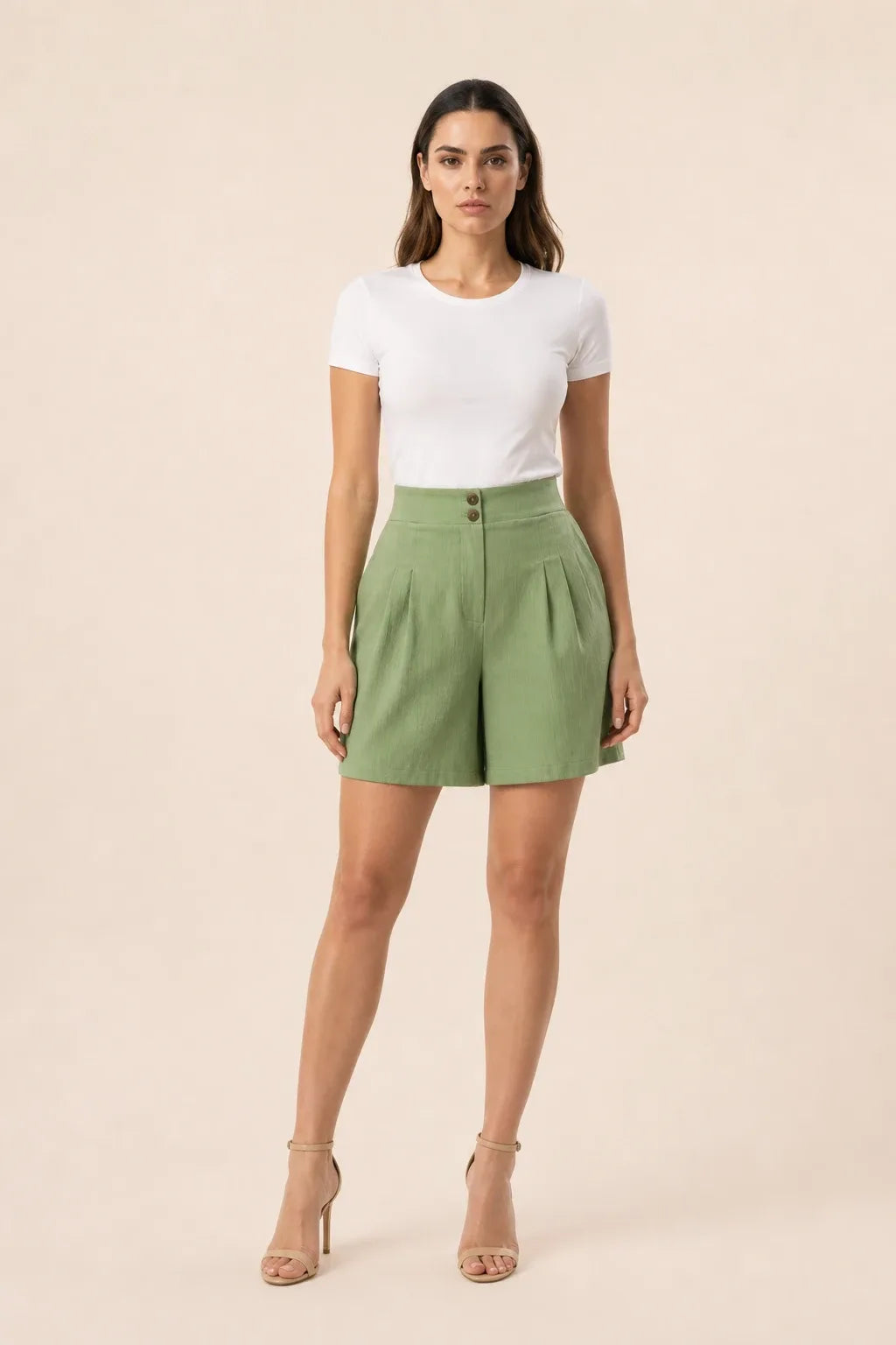 Light green pleated Bermuda shorts on a model in a contrapposto stance
