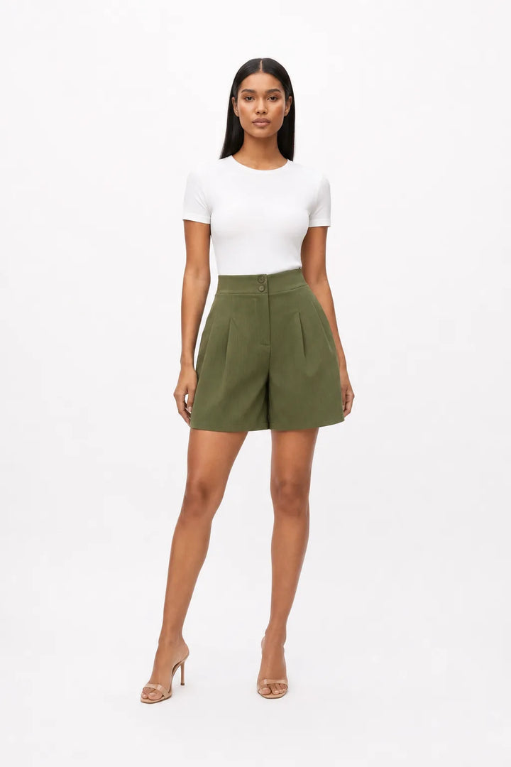 Olive green pleated Bermuda shorts on a model in a contrapposto stance