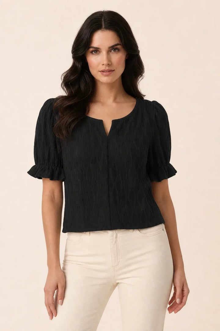 Black puff sleeve blouse on model in contrapposto stance, relaxed hip shift with arms at sides