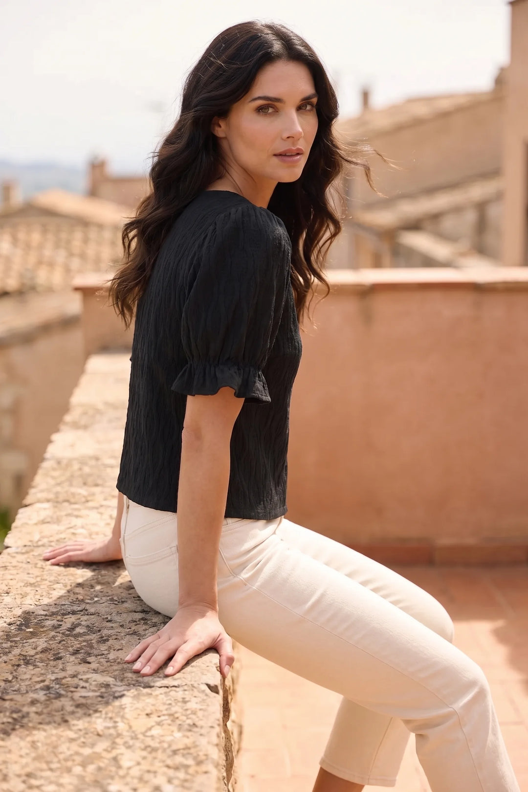 Model in black puff sleeve blouse captured in second lifestyle shot, casual relaxed mood