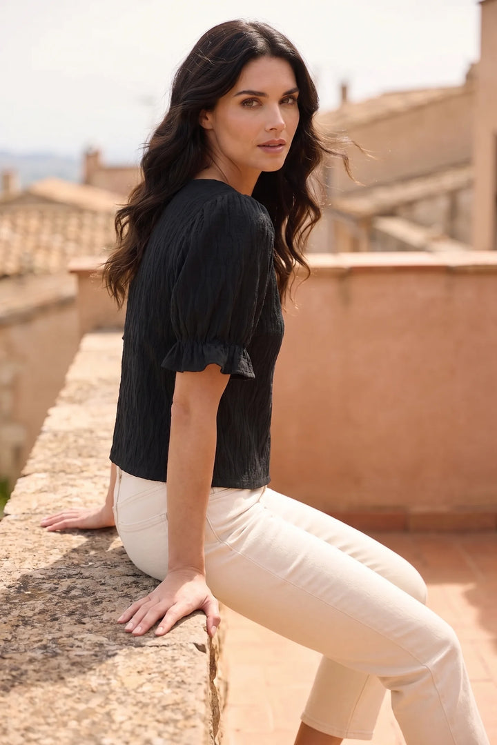 Model in black puff sleeve blouse captured in second lifestyle shot, casual relaxed mood