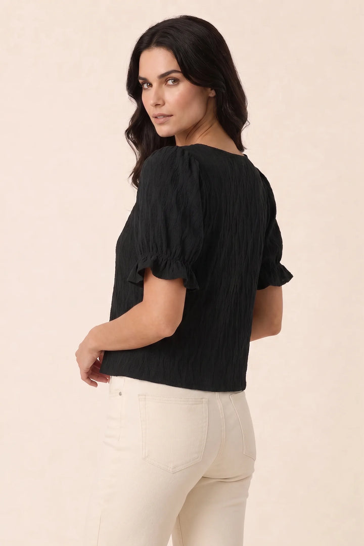 Black puff sleeve blouse on model in three-quarter turn, showing side silhouette