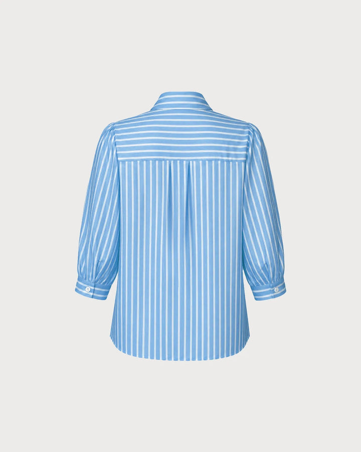 Woman wearing a blue puff sleeve blouse, side profile view
