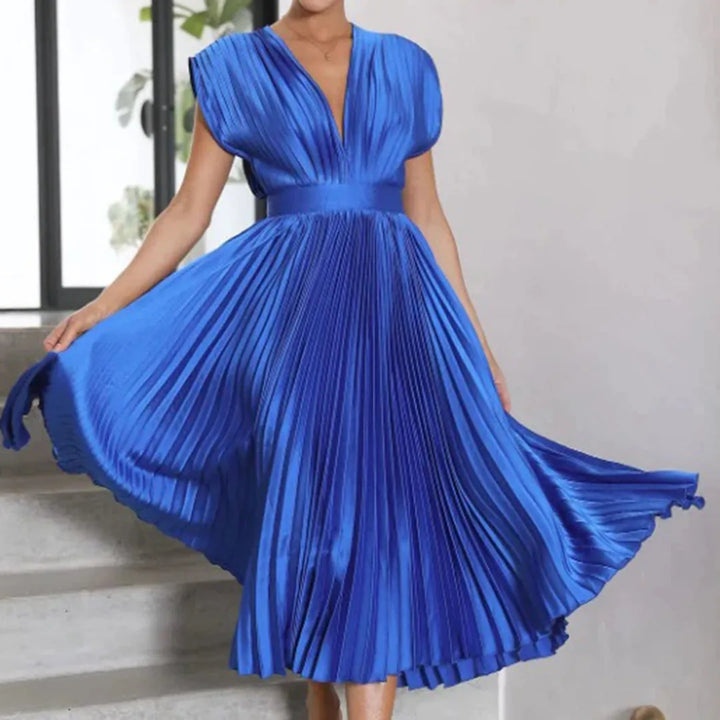 Model posing in a blue pleated midi dress with fluid pleated skirt