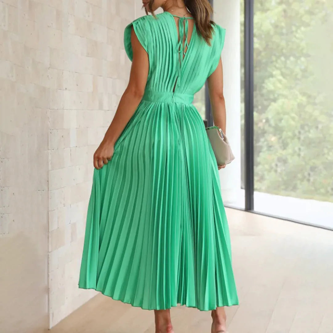 Model wearing champagne pleated midi dress in a relaxed stance