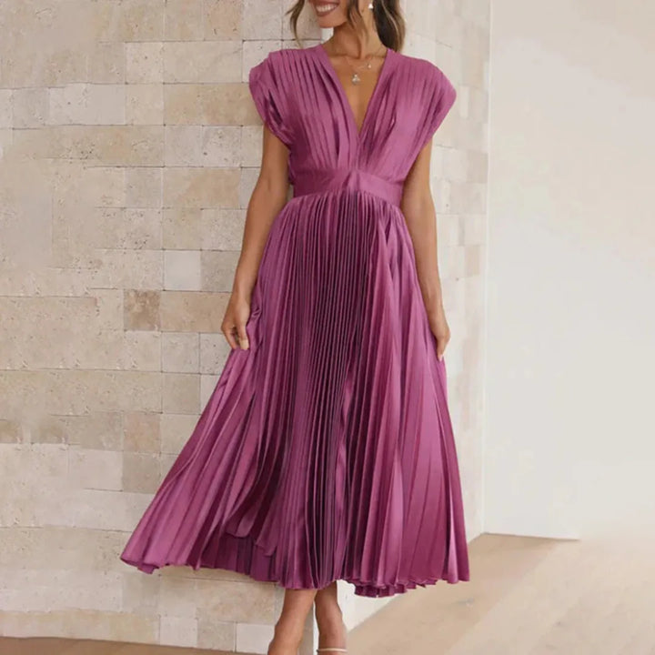 Model at three-quarter turn in a plum pleated midi dress with elegant drape